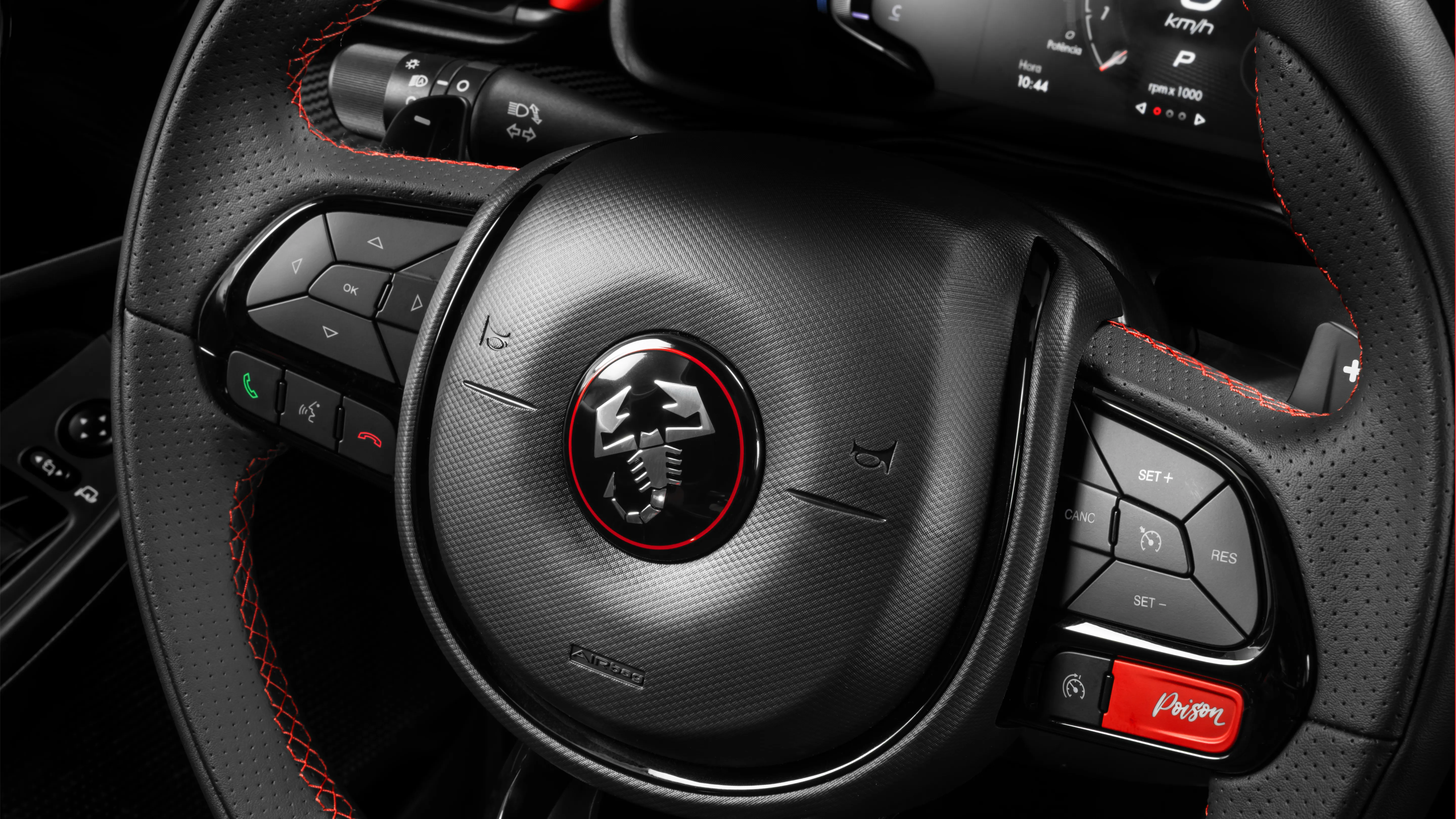 Zoom no volante do Fastback Abarth, que possui acabamento em couro com costura vermelha, com destaque para botão vermelho, escrito “Poison”, que ativa a direção esportiva do carro.