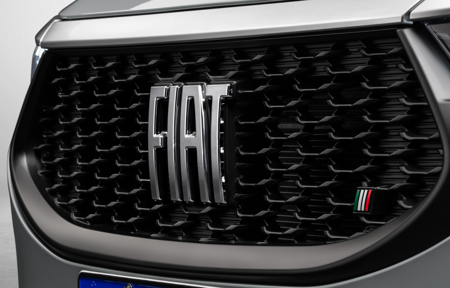 Grade preta frontal do Fiat Fastback com destaque para o logo tipográfico da Fiat e emblema pequeno, no canto inferior direito, com as cores da bandeira italiana.